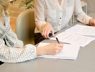 Two women writing and looking at a document